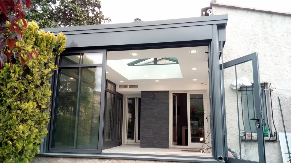 Extension vitrée à structure aluminium anthracite avec toiture vitrée, réalisée par VOLUMECREATION.